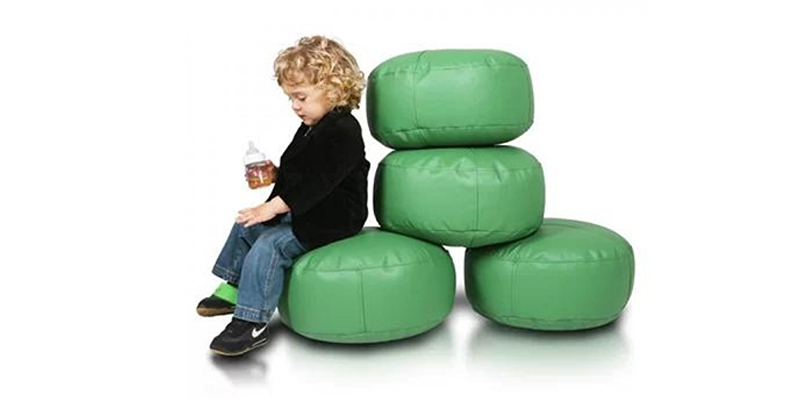 Мальчик сидит на пуфах зеленого цвета